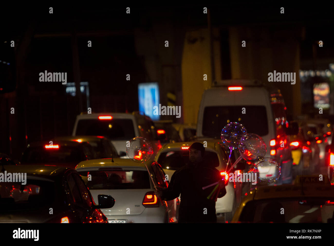 Vendor man sells led-light balloons at night at highway during a traffic jam in Altunizade, Asian side of Istanbul. Stock Photo