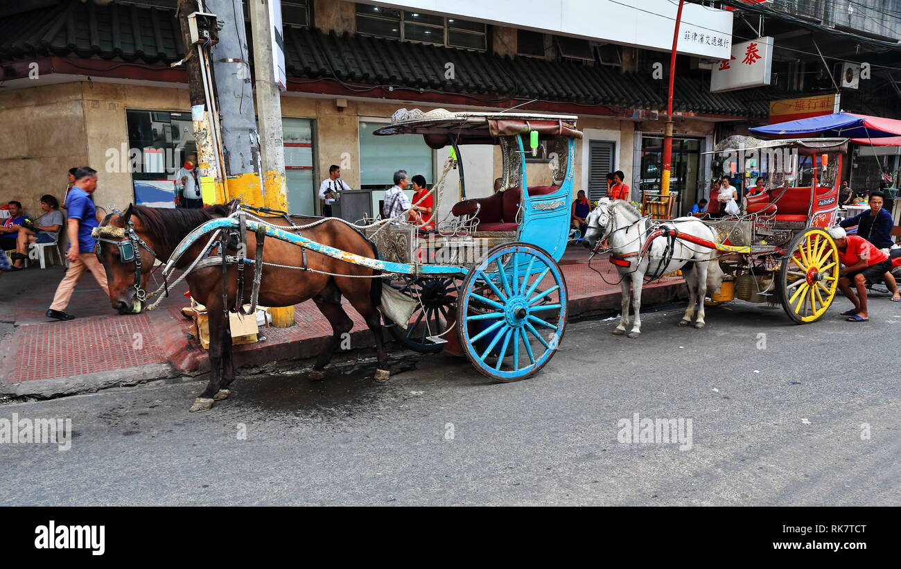 Manila, Philippines-October 24, 2016: Horse drawn kalesas-calashes stop at Ongpin just pass the North Bridge over the San Lazaro Estero while waiting  Stock Photo