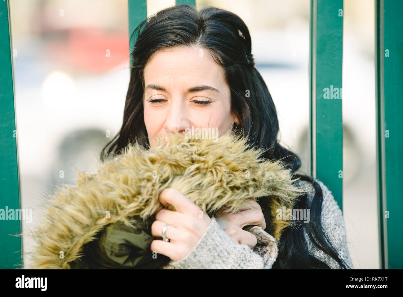 Portrait of brunette woman hugging her own coat to wrap herself up ...