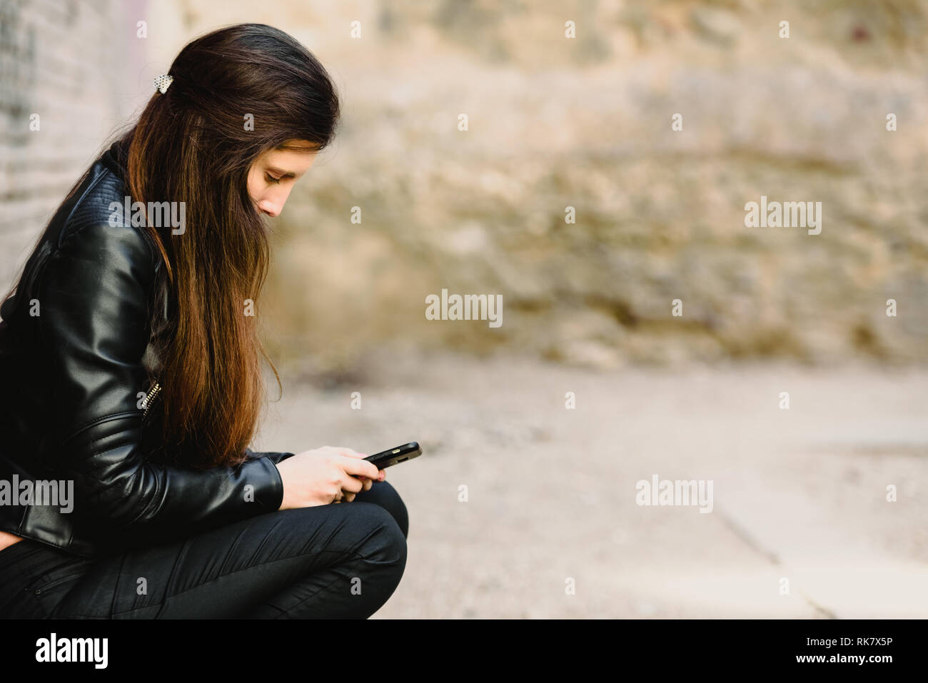 Sad teenage girl feeling lonely, looking at smartphone reading