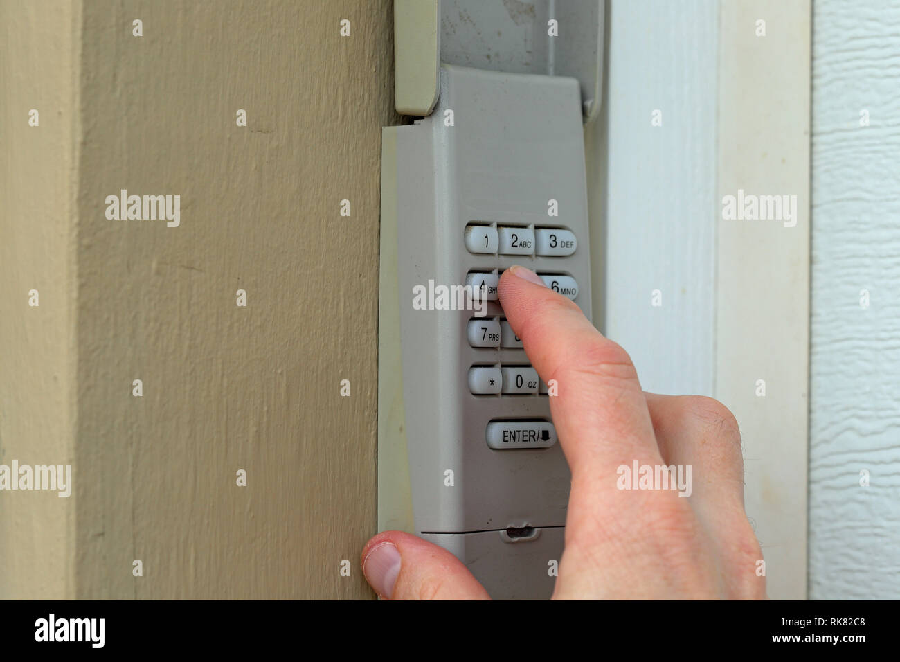 Hand enters code on keypad used on a garage door entrance to a home