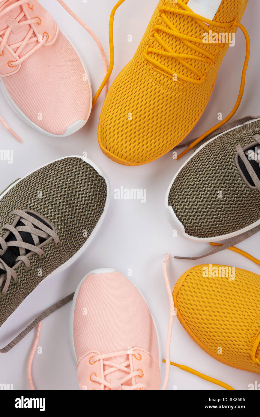 Sport shoes theme. Yellow, brown and pink running shoes on white background top view Stock Photo