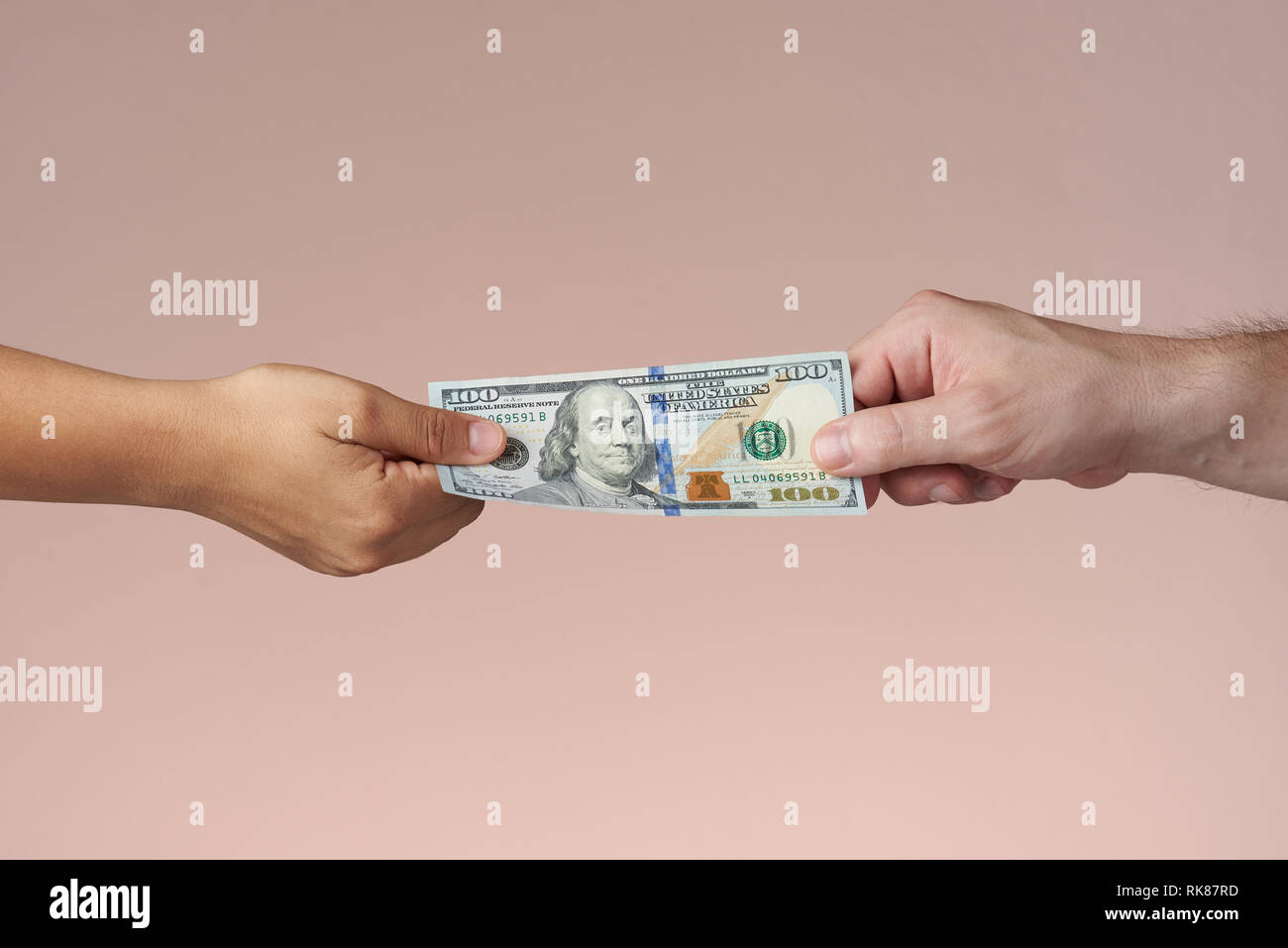 Two hands holding dollar bill. Hands sharing US money. Paying or trading concept. Stock Photo