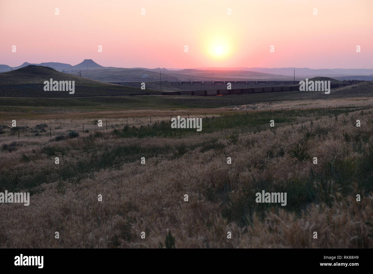 Empty high plains landscape of hills and coal train at sunset in the
