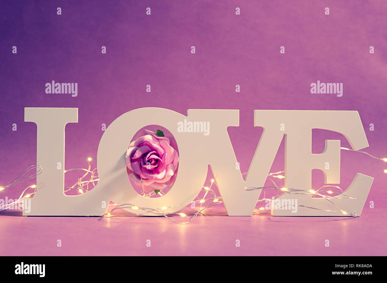 White love text wood and led light with pink rose on wooden background. Valentine concept. Stock Photo