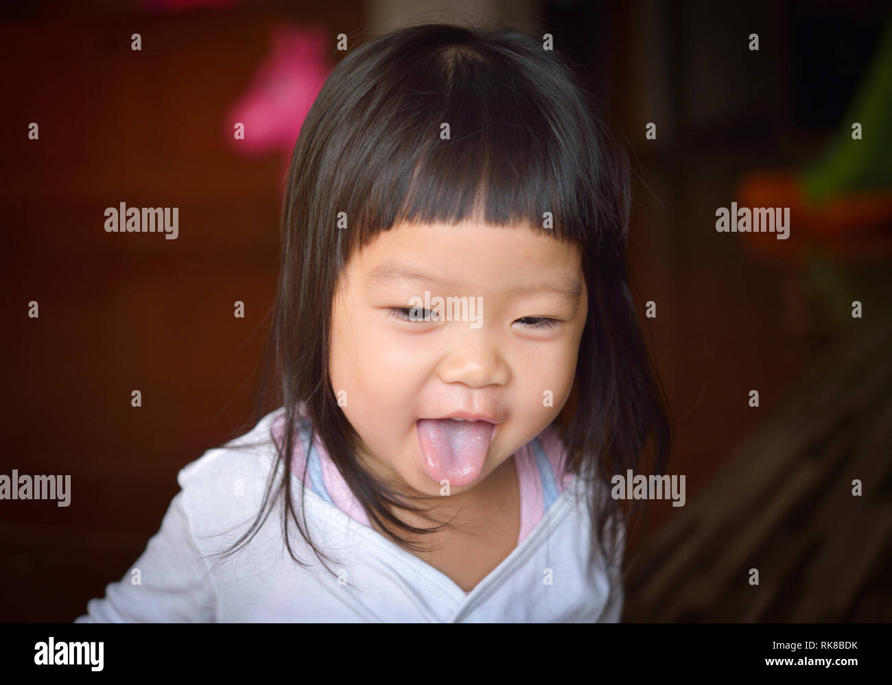asian baby girl showing her tongue in the home Stock Photo