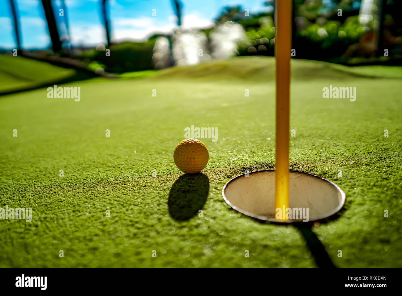 Mini Golf yellow ball on green grass at sunset Stock Photo