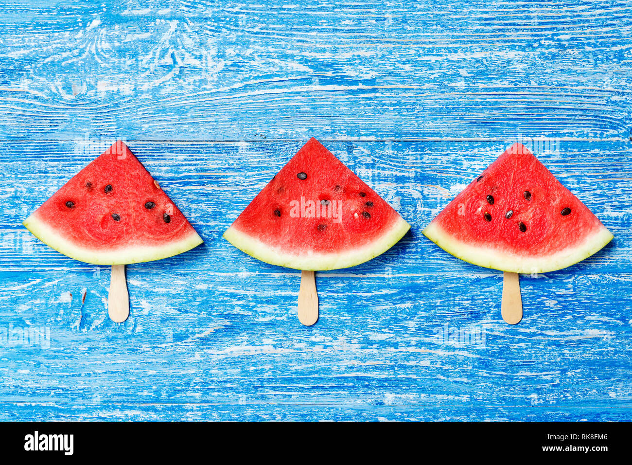 triangular slices of watermelon on a stick on a shabby blue background ...