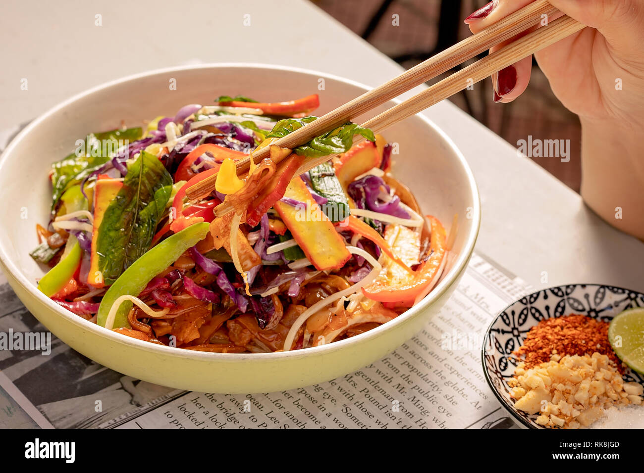 Taking a bit from the ready Thai dish using chopsticks Stock Photo