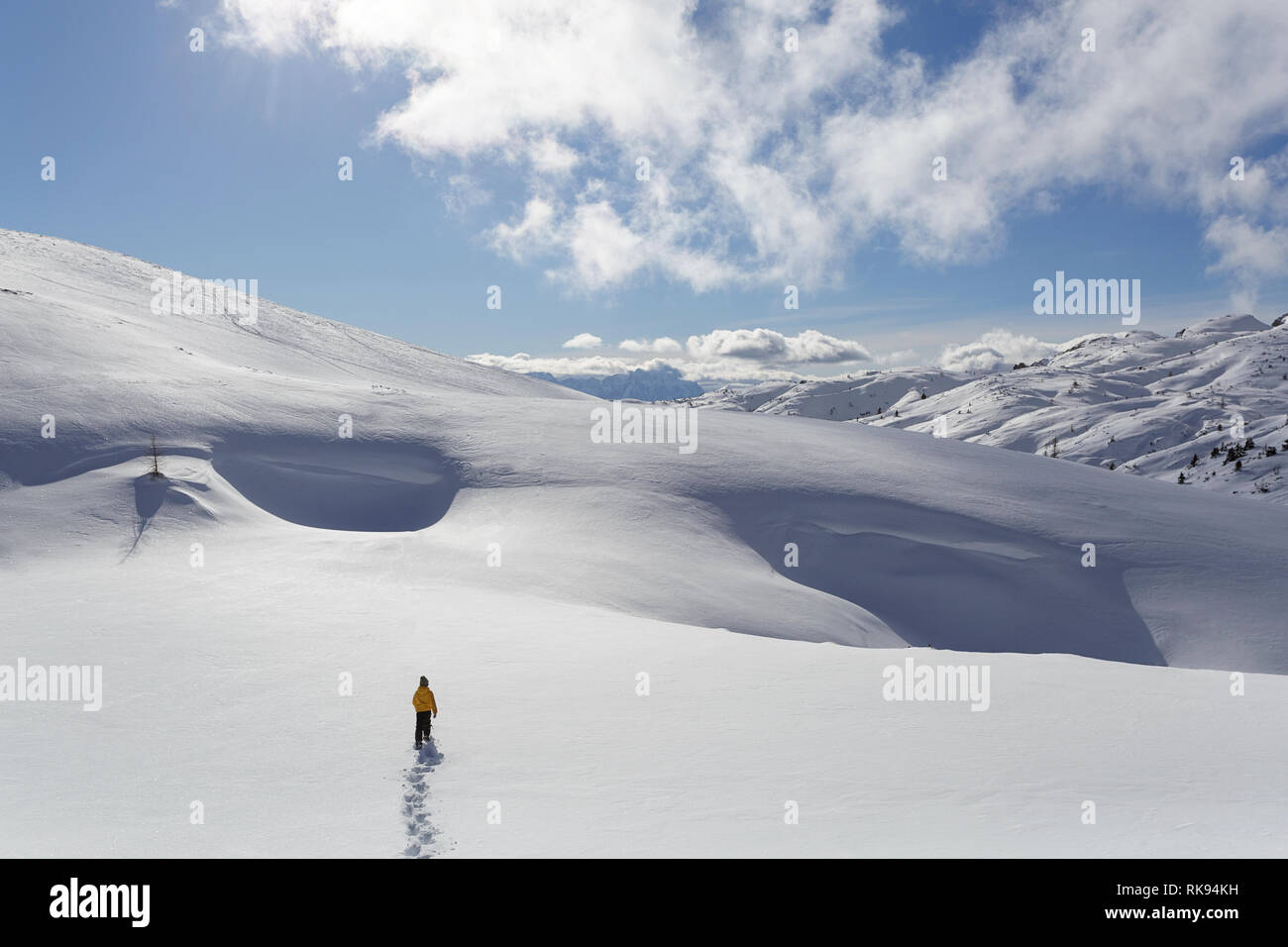 Young boy in yellow winter jacket walking in deep snow in snow covered winter mountain landscape, Dobratsch, Austria Stock Photo