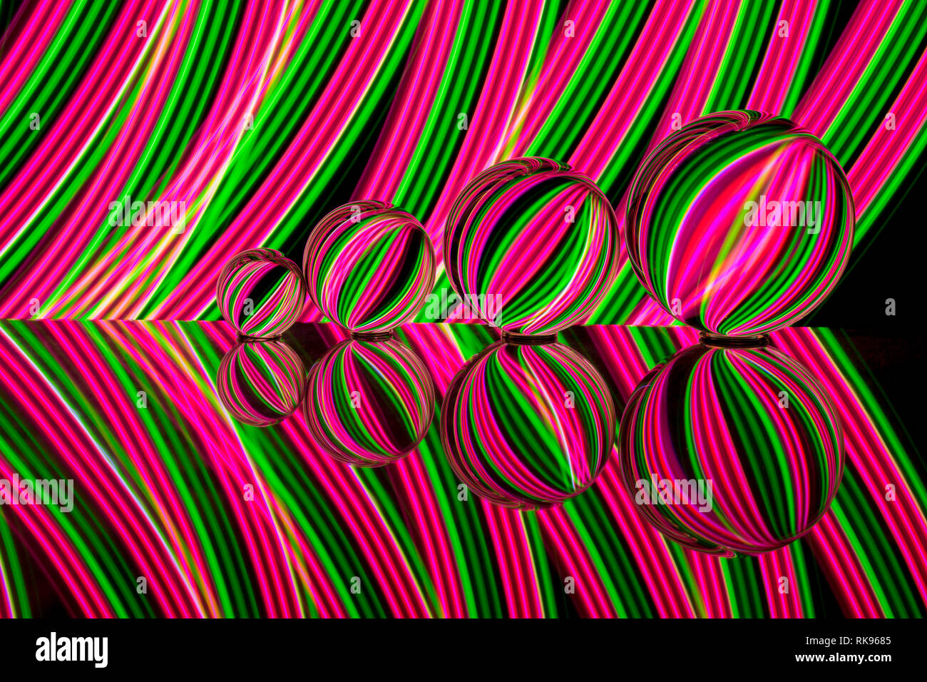 Four different size crystal / glass / lens balls in a row reflecting in