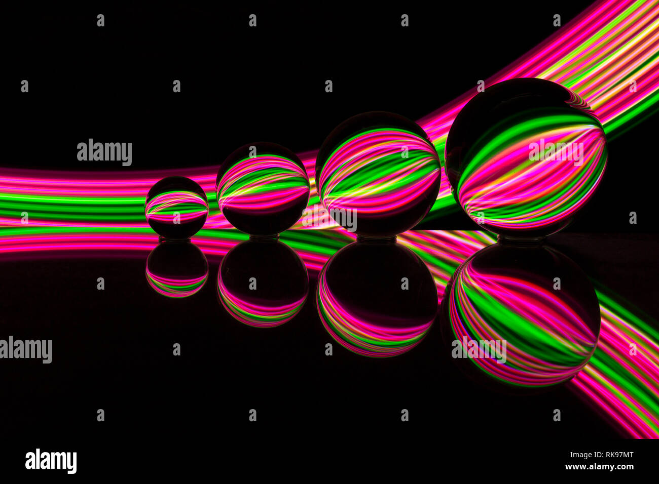 Four different size crystal / glass / lens balls in a row reflecting in