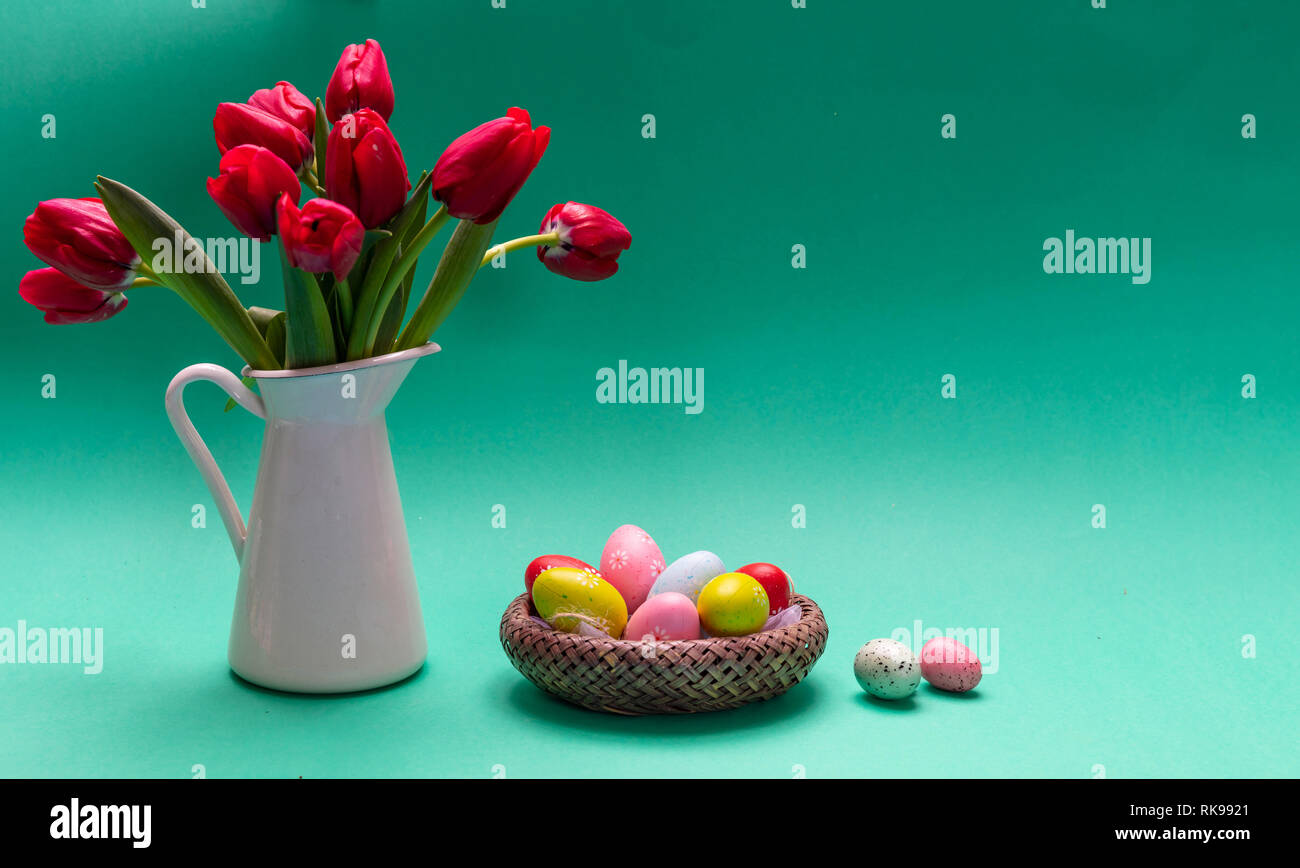 Easter eggs, pastel colors painted and tulips in a vase, green ...