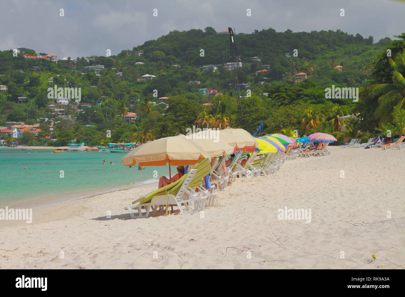 Sun beds and umbrellas on sand beach. St. George's, Grenada Stock Photo