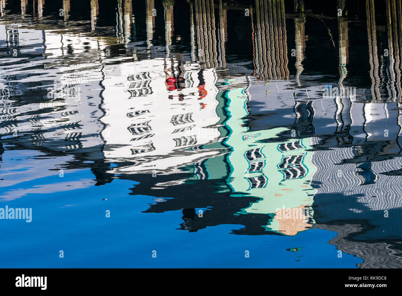 Pier at harbor in Henningsvaer, reflections of wooden houses in the calm water, Austvagöy, Lofoten, Norway Stock Photo