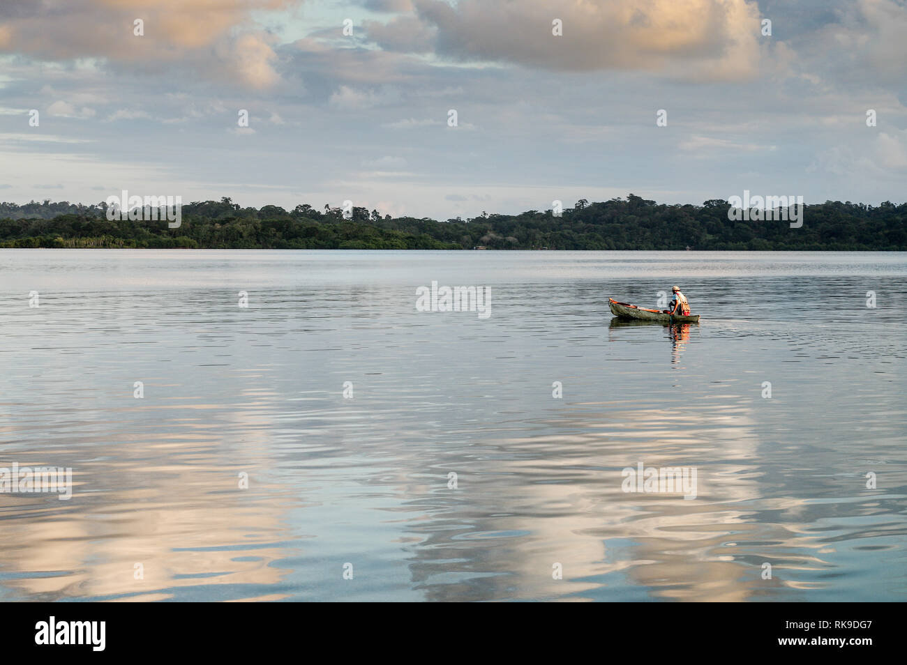 Man canoeing past Cristobal Island in Bocas Del Toro, with Tierra Oscura (mainland Panama) in the background Stock Photo