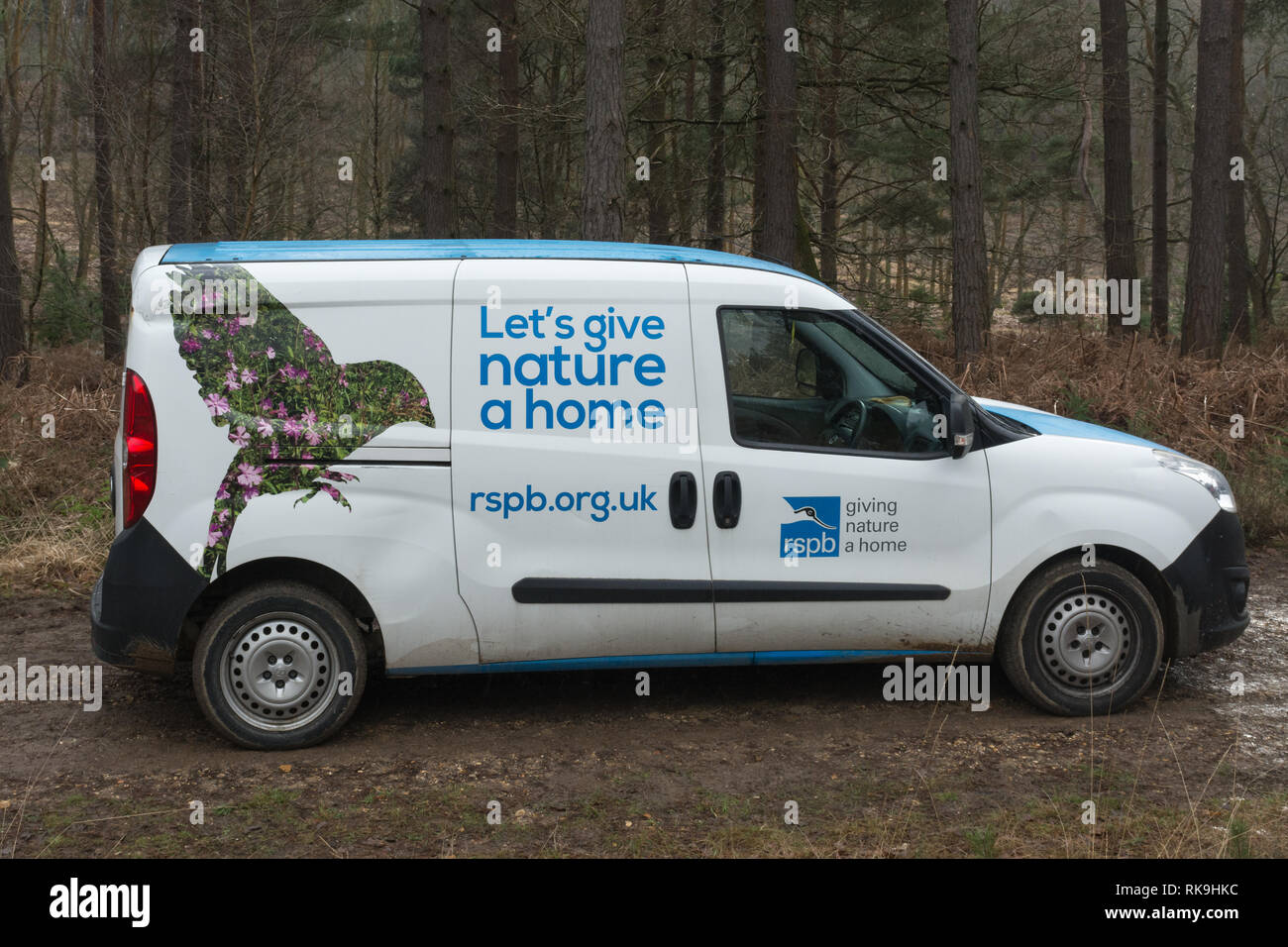 An RSPB van or vehicle parked in woodland with the logo Let's give nature a home. Stock Photo