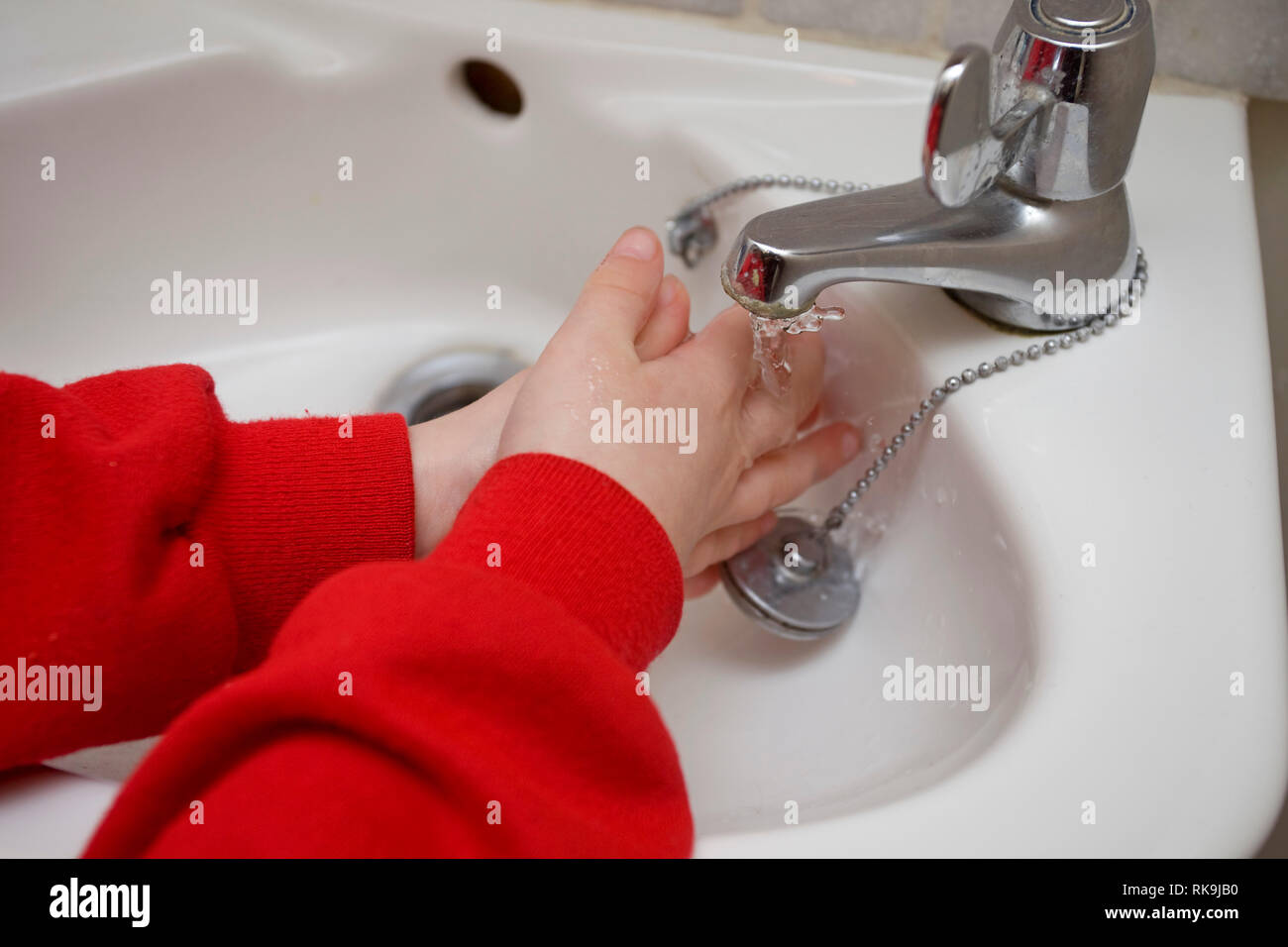 Child washing her hands under water tap Stock Photo