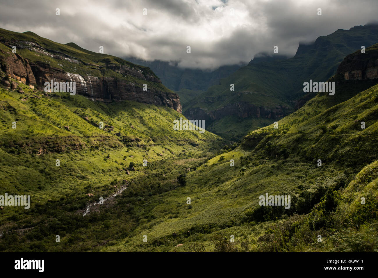 Cliffs, hills and the Tugela River in dramatic afternoon light, along the Tugela Gorge hiking route at the base of the Amphitheatre mountain. Drakensb Stock Photo