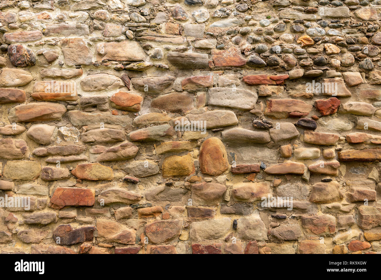 Old brick and stone wall with thick grout and very rough, irregular