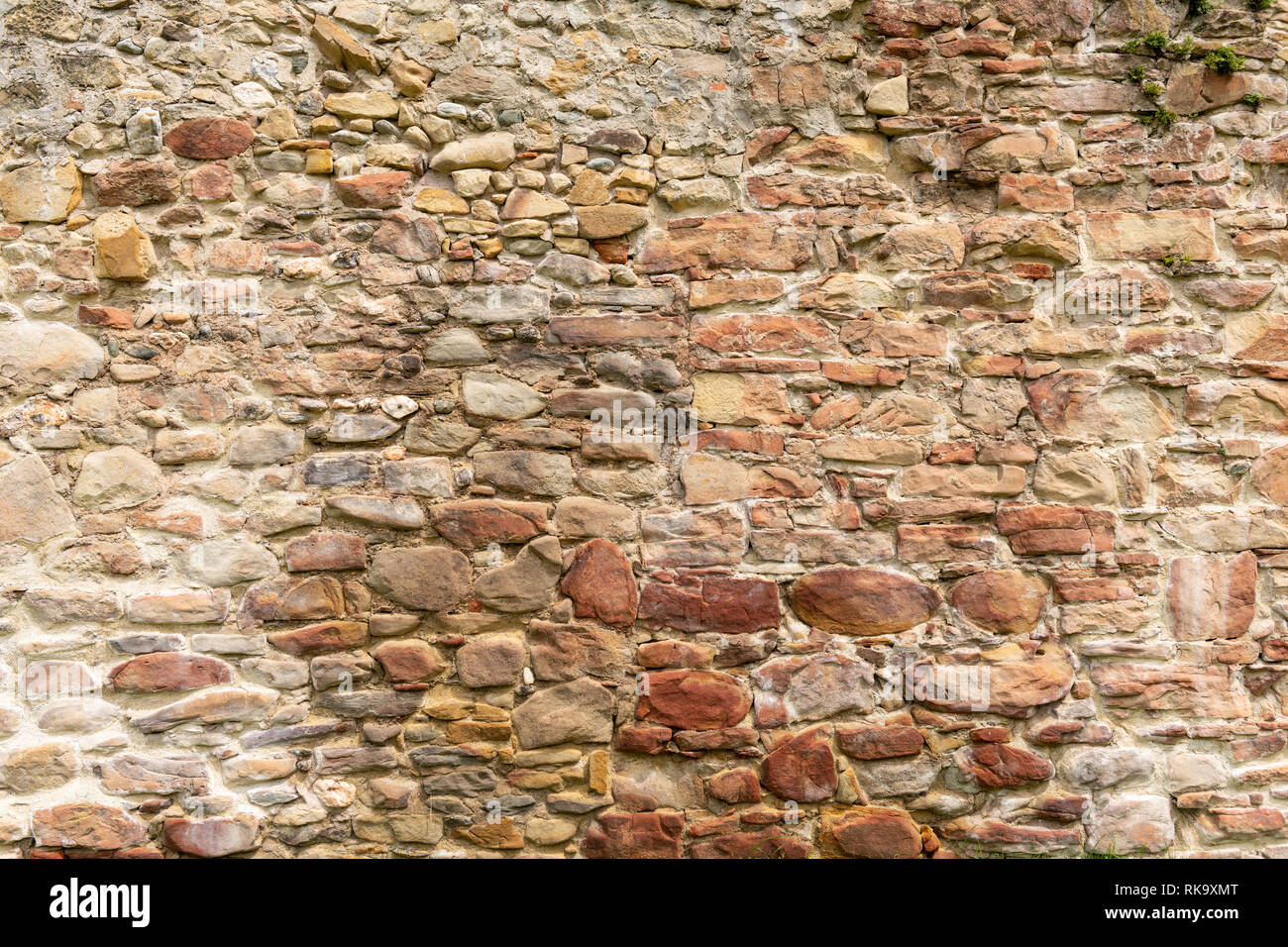 Old brick and stone wall with thick grout and very rough, irregular