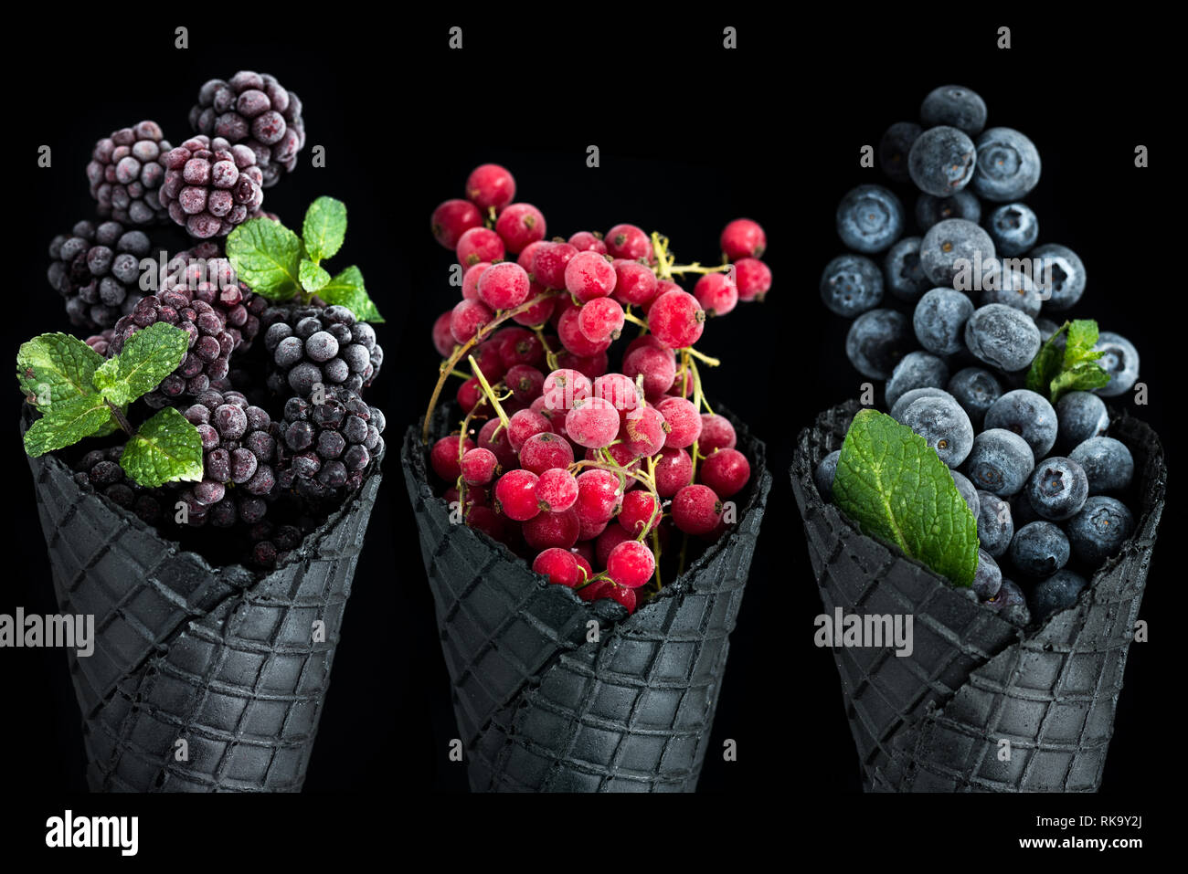 Black ice cream cones filled with fresh fruits. Stock Photo