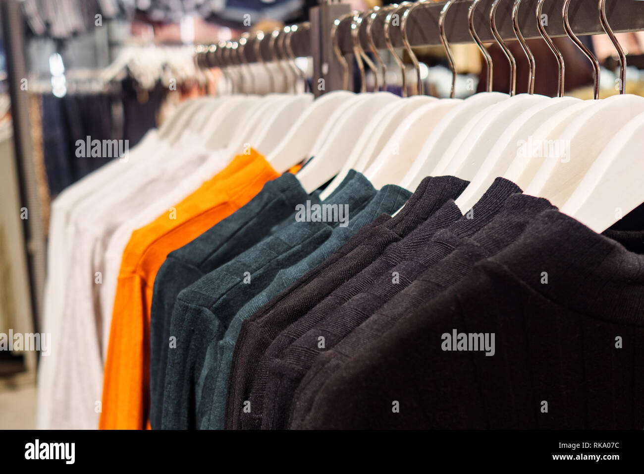 Stylish multicolored sweaters on rack Stock Photo - Alamy