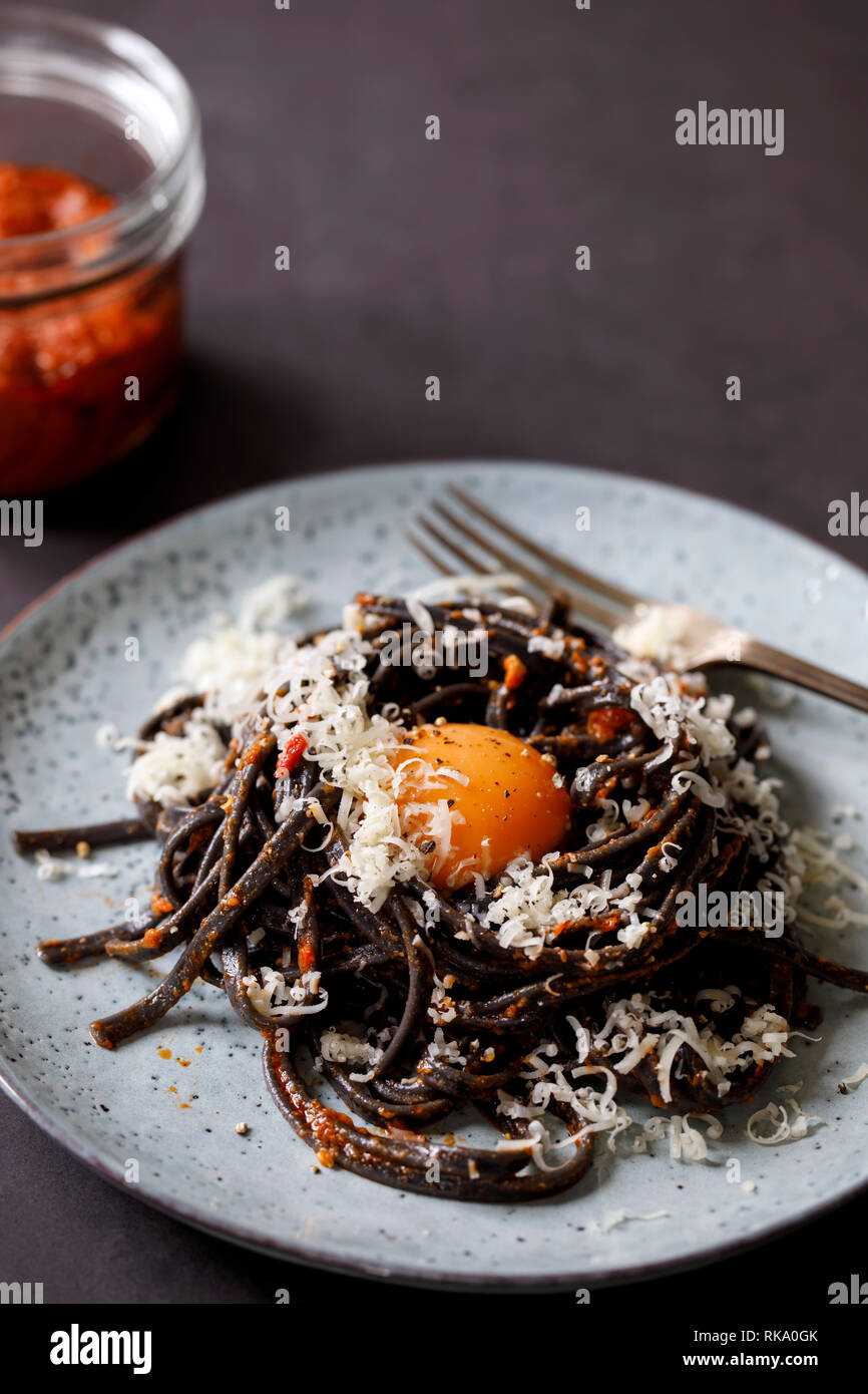 Black pasta with red pesto and egg yolk Stock Photo Alamy