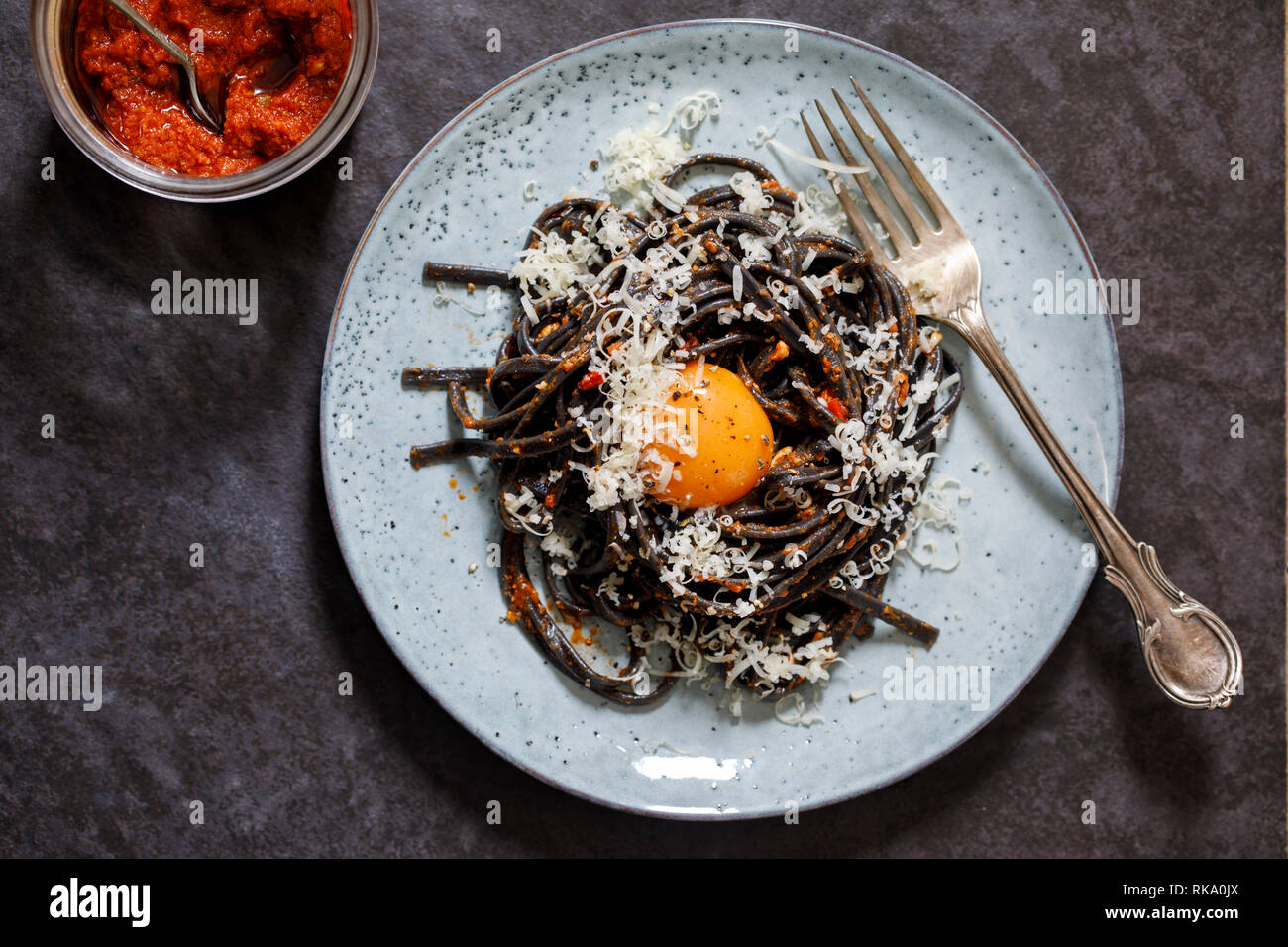 Black pasta with red pesto and egg yolk Stock Photo Alamy