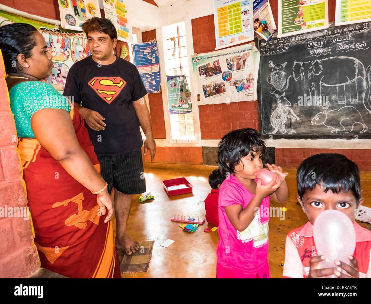 PUDUCHERY, INDIA - DECEMBER Circa, 2018. Poor preschool teacher and her group of kids boys girls having some fun at school with just a few wood toys g Stock Photo