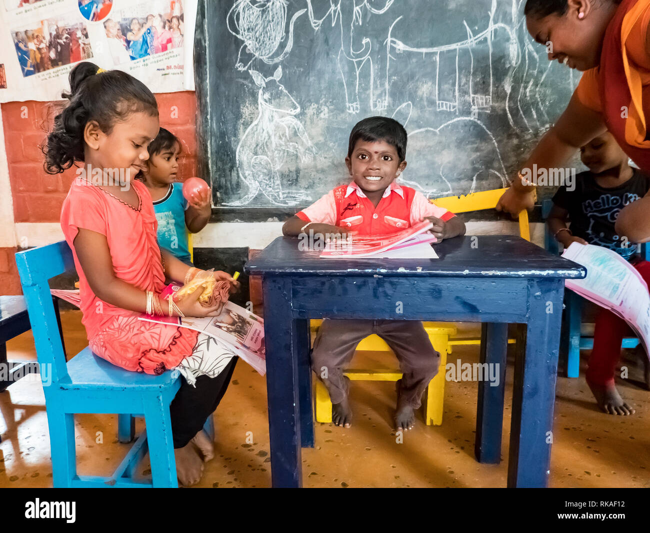 PUDUCHERY, INDIA - DECEMBER Circa, 2018. Poor preschool teacher and her group of kids boys girls having some fun at school with just a few wood toys g Stock Photo