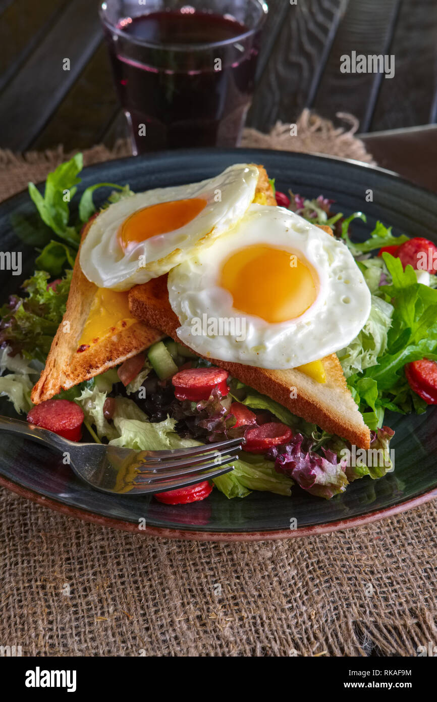 Fried eggs with toast, melted cheese and salad leaves Stock Photo