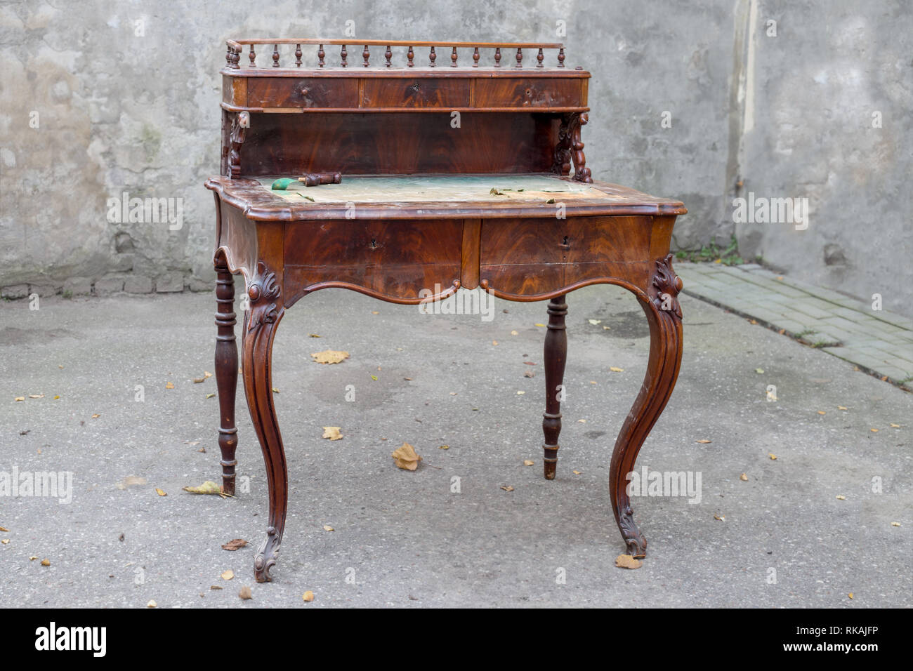 Antique mahogany writing desk with ornate carving, damaged Stock Photo