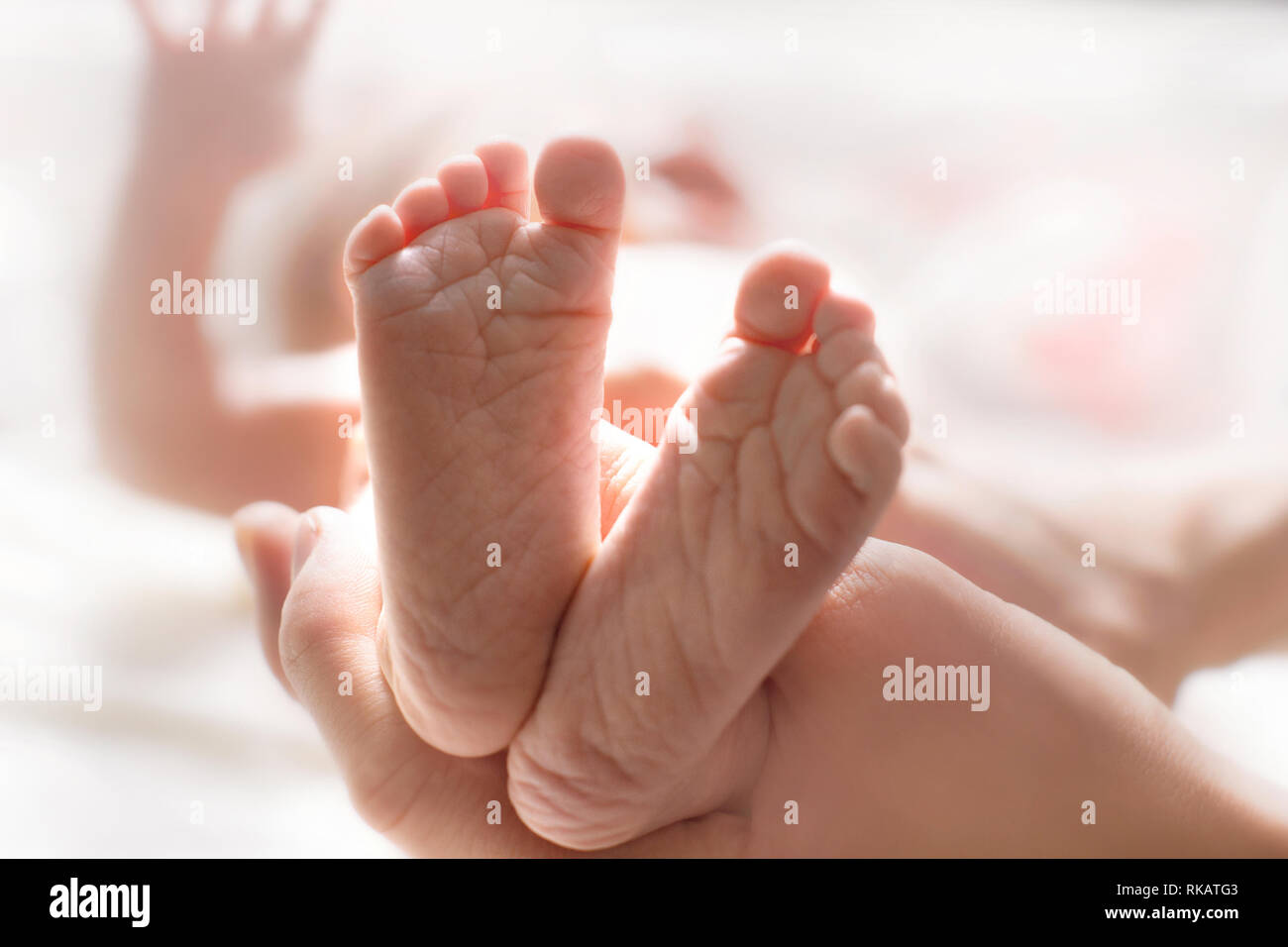 Mom massages the legs of a newborn baby. Baby feet in mother hands. Tiny  new born baby's feet on female hands closeup Stock Photo - Alamy