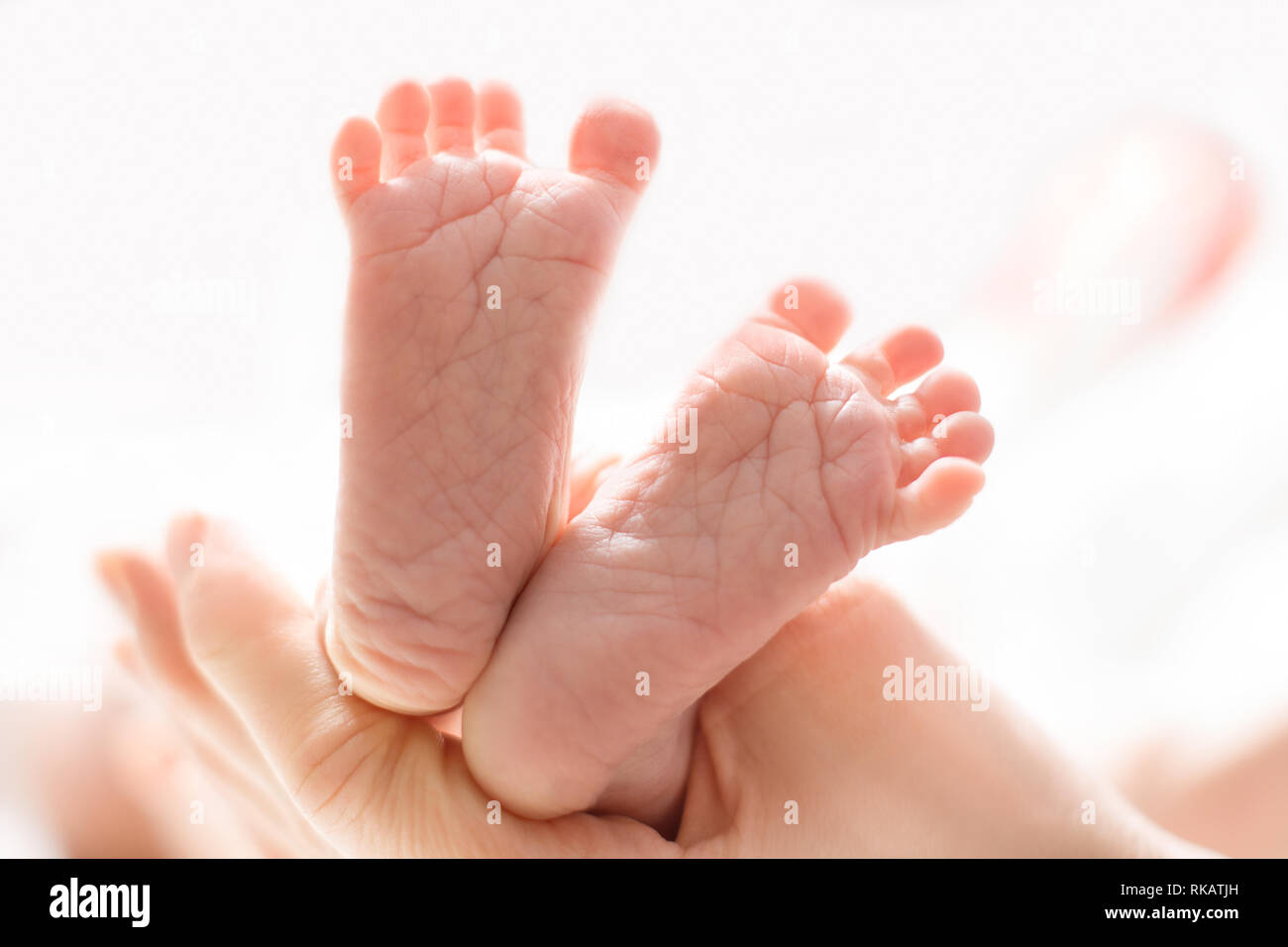 Mom massages the legs of a newborn baby.  Baby feet in mother hands. Tiny new born baby's feet on female hands closeup Stock Photo