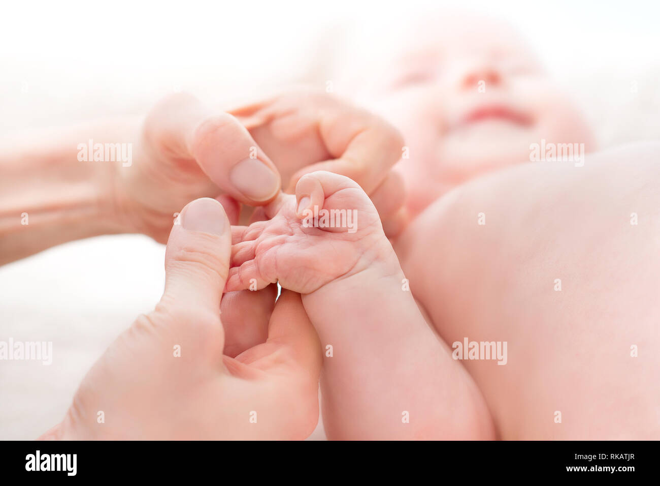 Mom massages the legs of a newborn baby.  Baby feet in mother hands. Tiny new born baby's feet on female hands closeup. Mommy and her child. Happiness Stock Photo