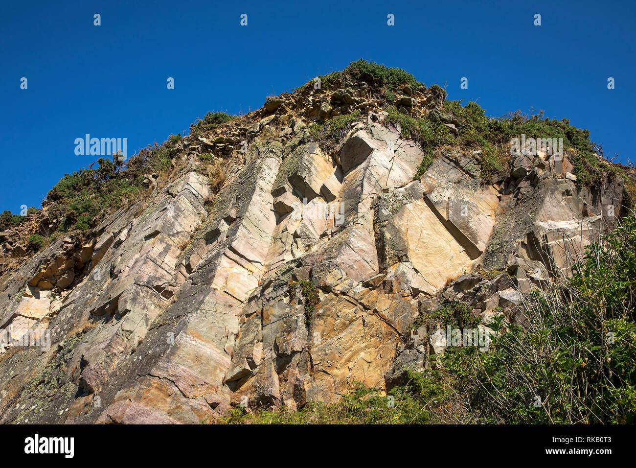 One side of Mannez quarry on Alderney, showing the large naturally formed stone blocks that were mined in quantity for the breakwater. Stock Photo