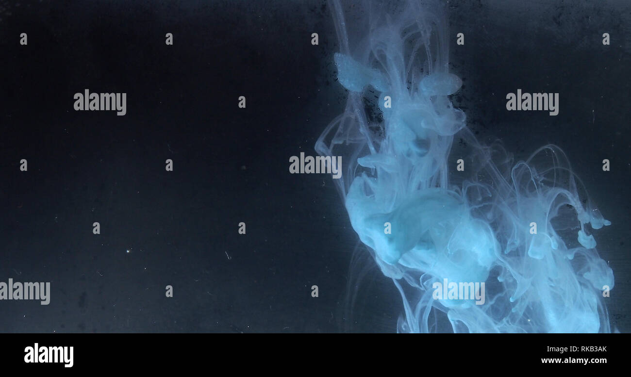 A drop of paint dissolves in water. On black background. Abstract ...