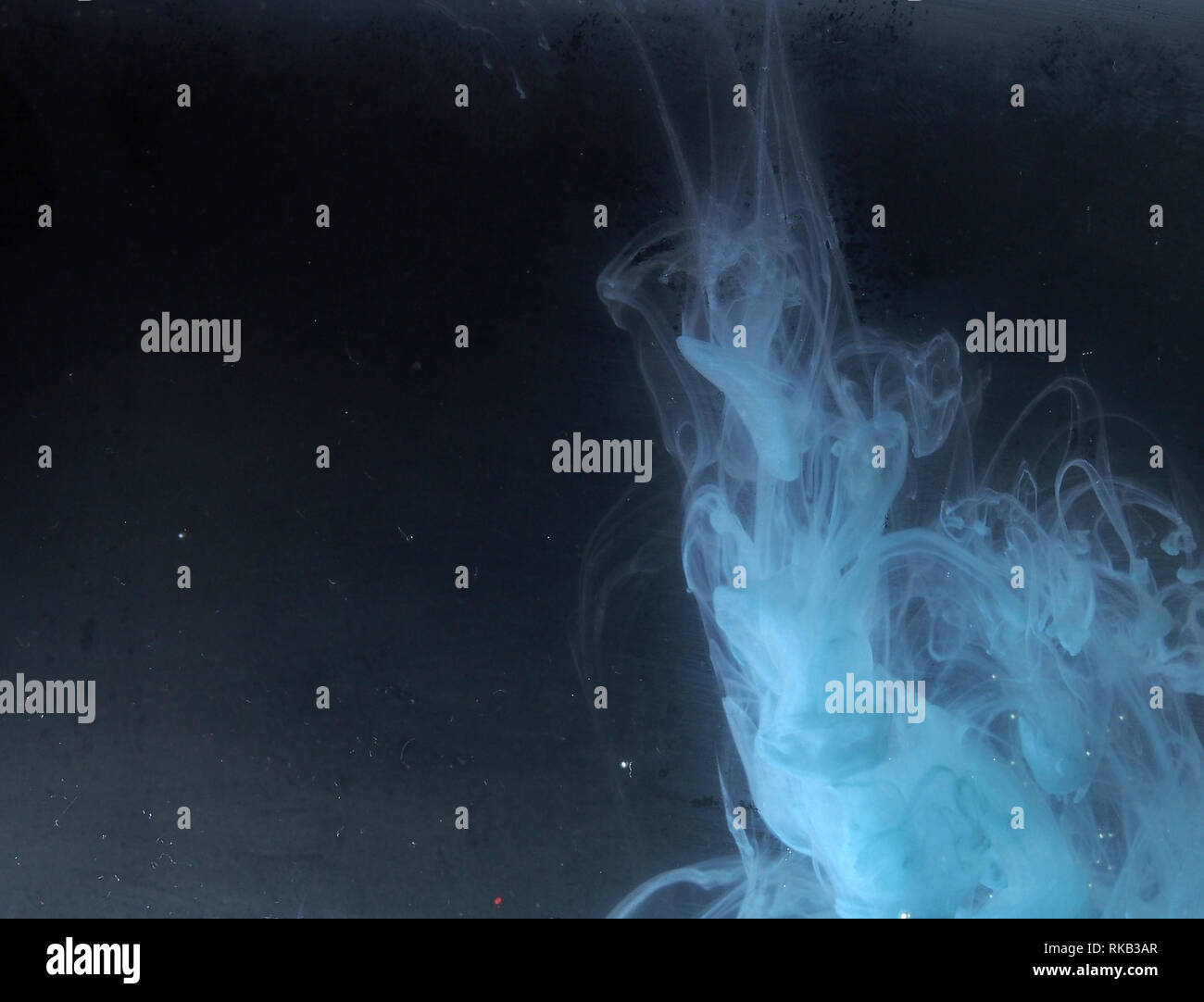 A drop of paint dissolves in water. On black background. Abstract