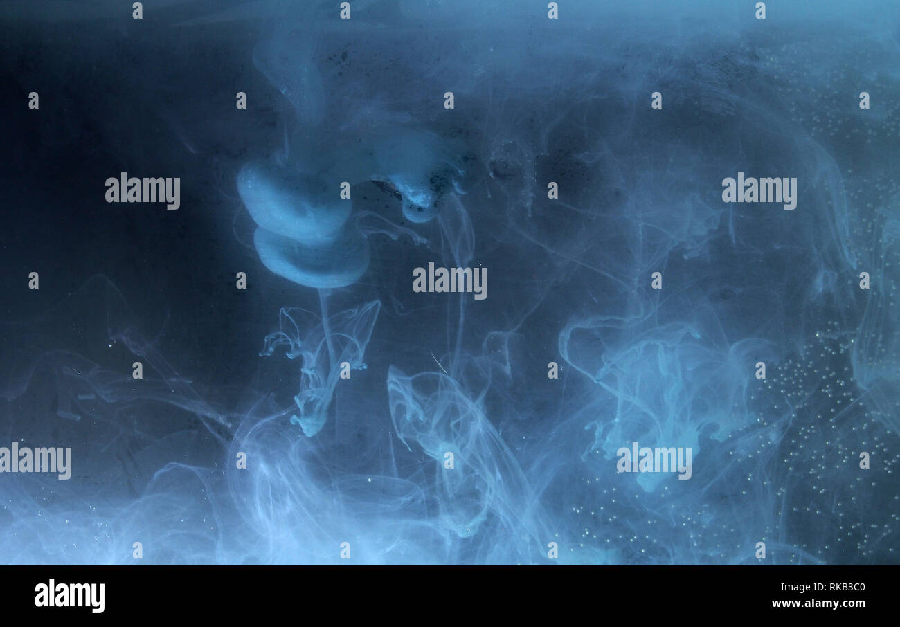 A drop of paint dissolves in water. On black background. Abstract ...