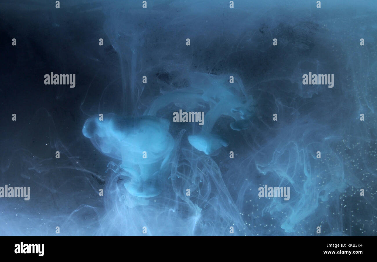 A drop of paint dissolves in water. On black background. Abstract