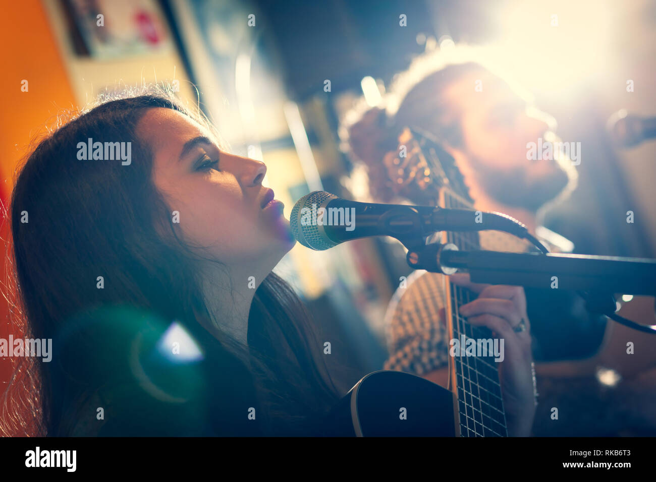 Duet of guitarists singing during a musical performance. Backlight with flare. Stock Photo