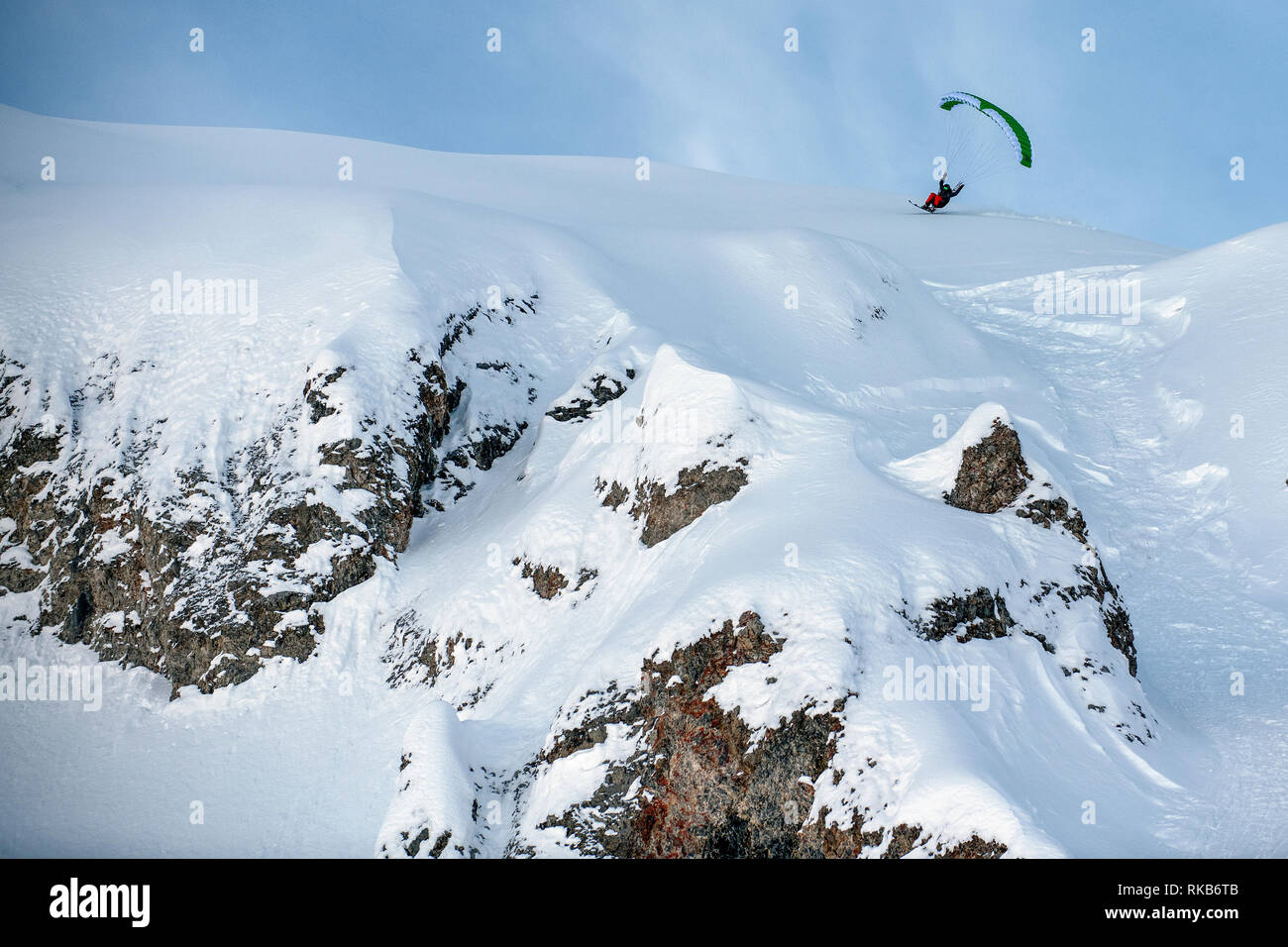 Speed-flying in the French alpine resort of Courchevel. A man flies using a speed-flying wing on skis off a cliff on snow. Stock Photo