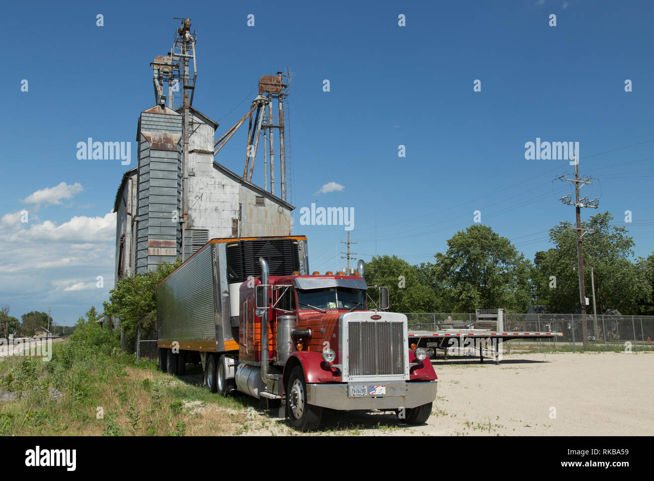 An old semi trailer sits below an aged grain elevator in the rural town of Mazon Illinois. Stock Photo