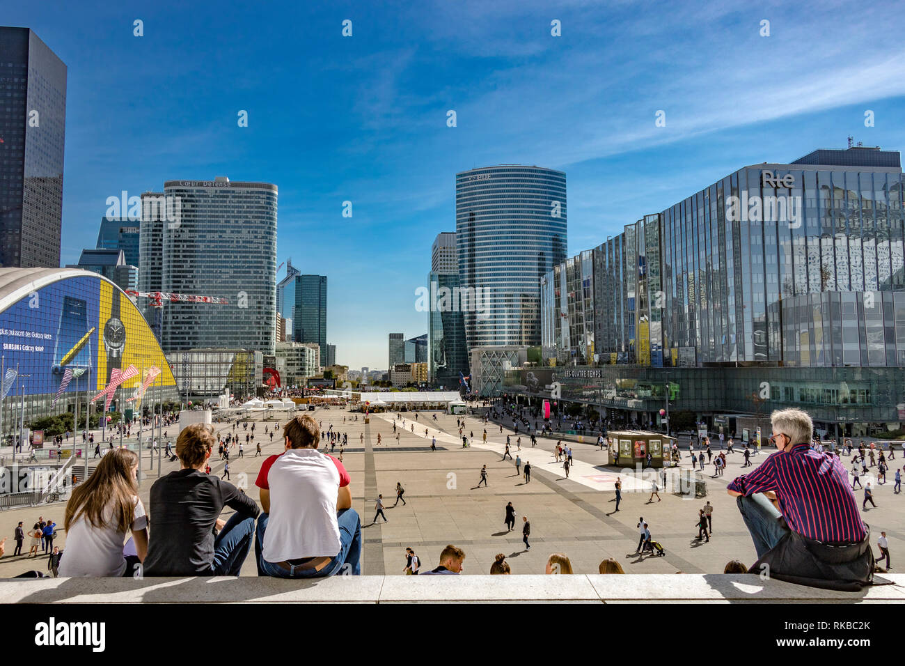 Crowds of people sitting on the steps of La Grande Arche de la Défense enjoying the warm sunshine on a hot summer's day in La Défense ,Paris,France Stock Photo