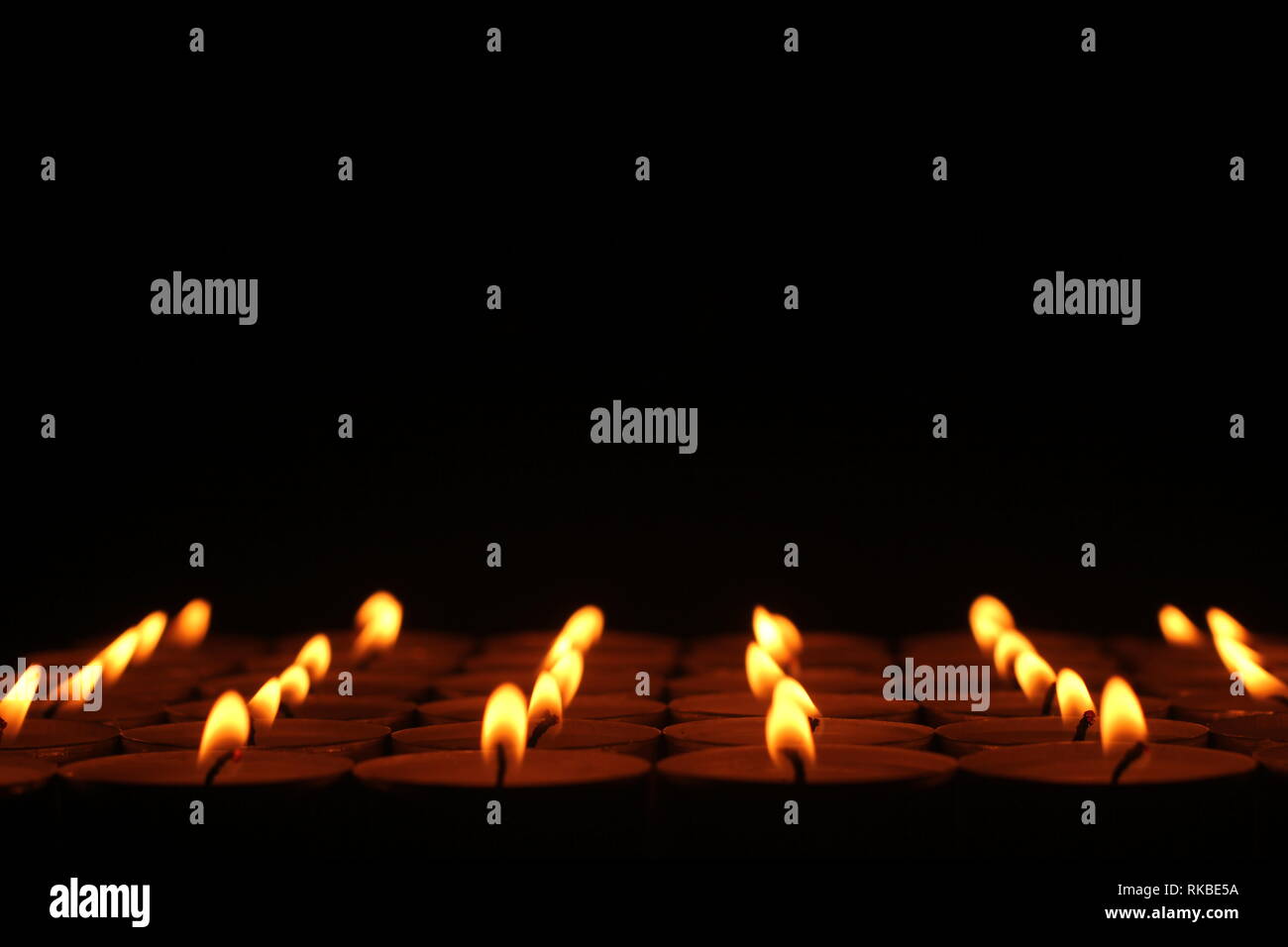 A royalty free image of rows of candles that seem to go one forever, with a black top portion. Stock Photo
