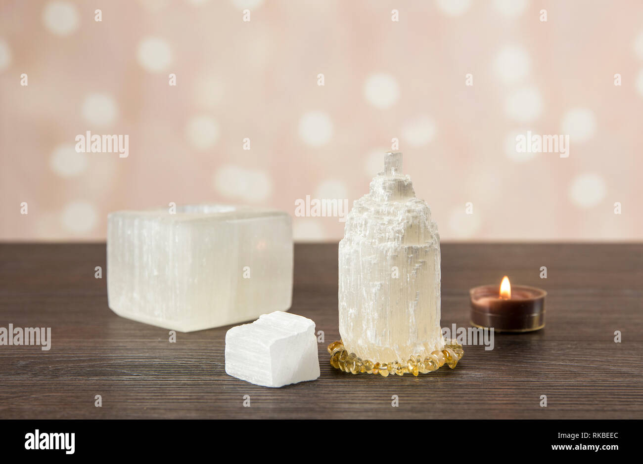 Naturally carved mineral stone Selenite tower has healing on cleansing properties. Candle holder, piece of raw and carved Selenite tower on dark woode Stock Photo