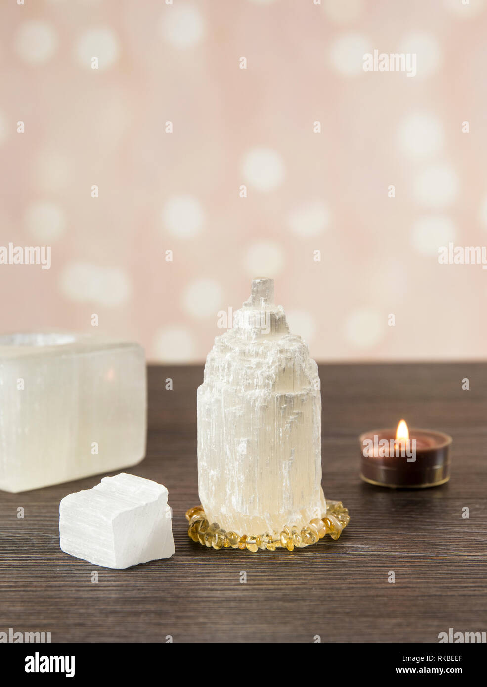 Naturally carved mineral stone Selenite tower has healing on cleansing properties. Candle holder, piece of raw and carved Selenite tower on dark woode Stock Photo