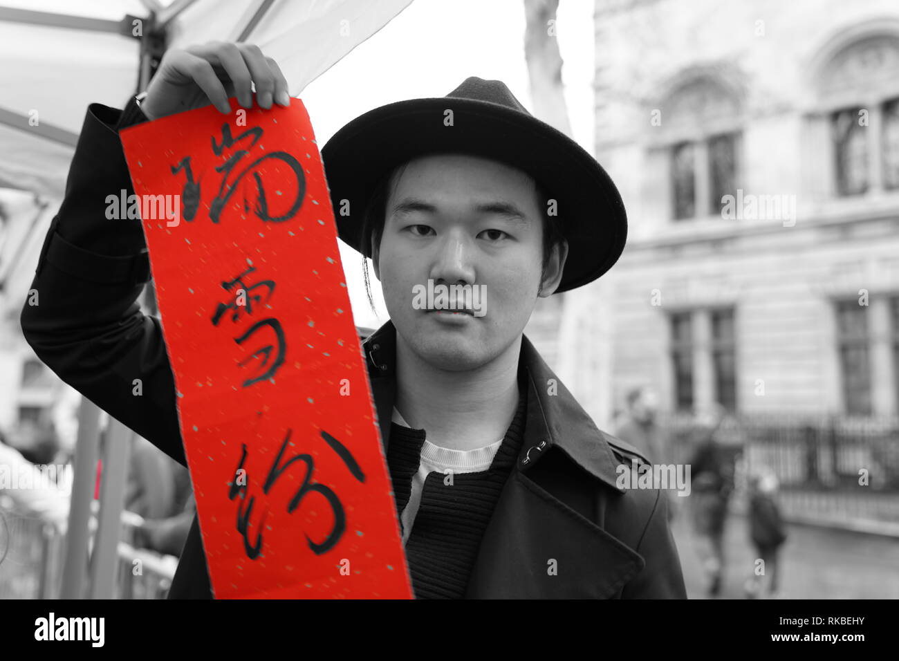During the 2019 Chinese New Year a British Chinese is holding a red rice paper with Chinese symbols that reflect his wishes for the new year Stock Photo