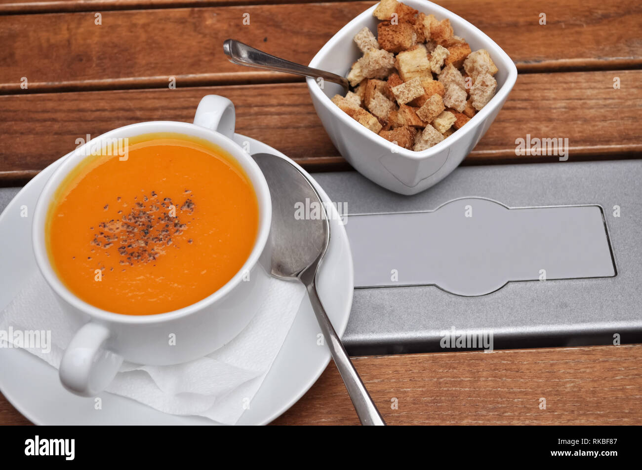 Yellow pumpkin soup puree and bread rusks in white plates on a wooden table  in a restaurant. Stock Photo